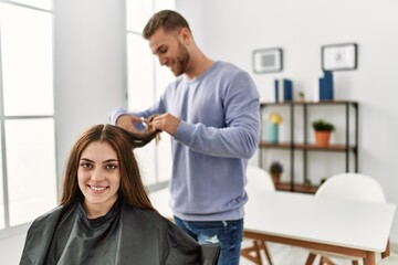 Young man cutting hair his girlfriend at home.
