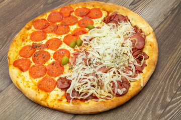 Big pizza with delicious ingerdietnes. Peperoni and calabrian. On a wooden table.