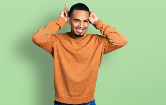 Young african american man wearing casual clothes posing funny and crazy with fingers on head as bunny ears, smiling cheerful