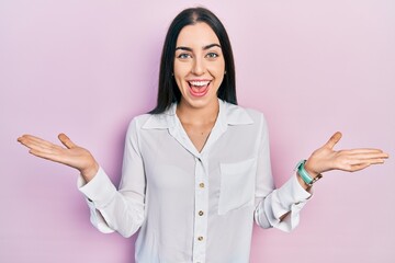 Beautiful woman with blue eyes wearing casual white shirt celebrating victory with happy smile and winner expression with raised hands