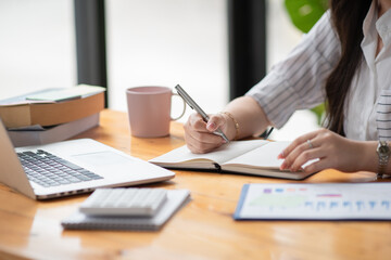 Female hands with pen writing on notebook.