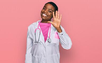 Young african american woman wearing doctor uniform and stethoscope showing and pointing up with...