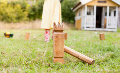 Kind spielt Wikingerschach (Kubb) im Garten. Child plays viking chess in the garden.