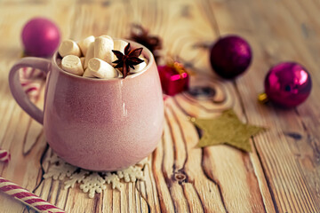 Christmas drink background, pink cup with hot chocolate and marshmallows on a wooden table near New Year's decor. Cocoa Christmas drink, copy space, bokeh effect, drink mug Christmas holiday 