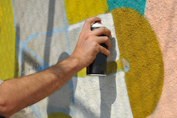  Street artist draws colorful graffiti on the concrete wall.