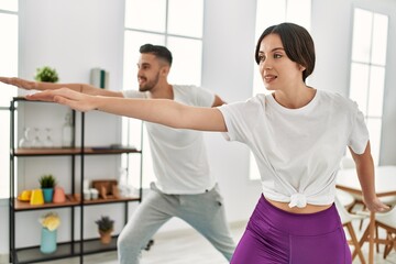 Young hispanic couple doing yoga at home