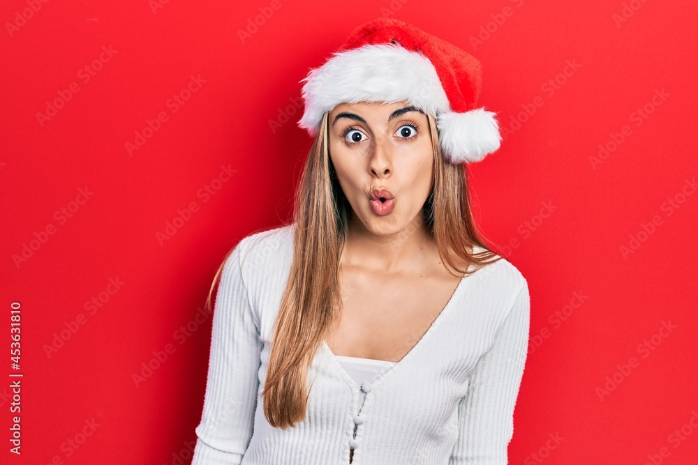 Sticker beautiful hispanic woman wearing christmas hat afraid and shocked with surprise expression, fear and