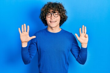 Handsome young man wearing casual clothes and glasses showing and pointing up with fingers number...
