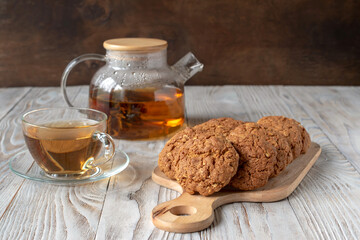 Homemade oatmeal cookies with glass teapot of green tea.