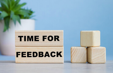 TIME FOR FEEDBACK word on wooden cubes on white desk.