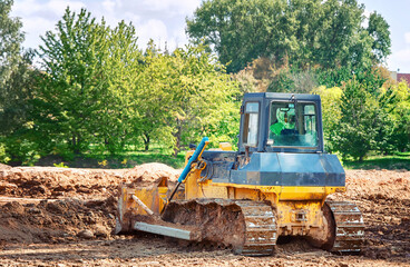 Dozer at construction site, earth works, heavy duty bulldozer leveling ground. Heavy machinery, level ground. Crawler dozer at construction site, rear view. © Tricky Shark