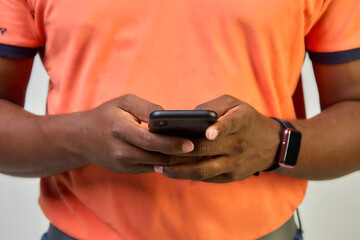 Close-up of an African-American man on a white background holding a smartphone, typing a message, communicating with friends or relatives, playing an online game, making purchases.