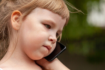Young child, little girl deep in thought talking on the mobile phone, smartphone. Natural portrait, neutral expression, face extreme closeup. Telecommunication, communication technology concept