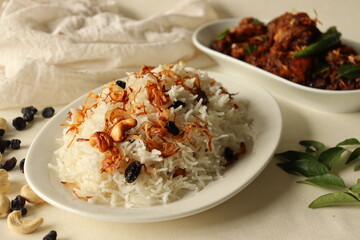 Rice dish made of Basmati rice, ghee and spices and garnished with fried onions served with Kerala style spicy chicken roast.