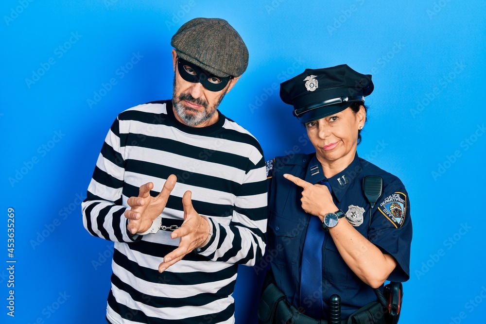 Sticker middle age couple of hispanic woman and man wearing thief and police uniform pointing with hand fing