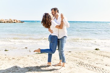 Middle age hispanic couple kissing and hugging at the beach.