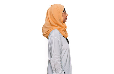 Middle age hispanic woman wearing traditional islamic hijab scarf looking to side, relax profile pose with natural face with confident smile.