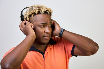 Young African American man wearing black wireless headphones and enjoying music on a white background