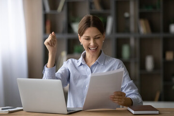 Overjoyed woman reading good news in letter, rejoicing success, job promotion, sitting at work desk...