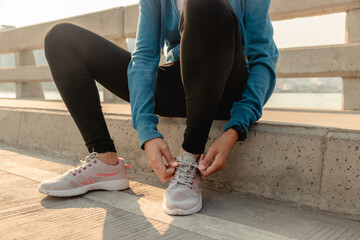 Close up Sport hands tying running shoes on street outdoors. Woman preparing for run exercise workout in the morning.