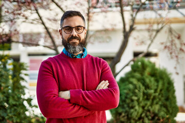 Young hispanic executive man smiling happy with arms crossed gesture at the city.