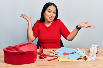 Beautiful hispanic woman with nose piercing doing handcraft creative decoration clueless and...
