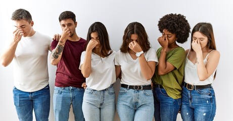 Fototapeta premium Group of young friends standing together over isolated background tired rubbing nose and eyes feeling fatigue and headache. stress and frustration concept.