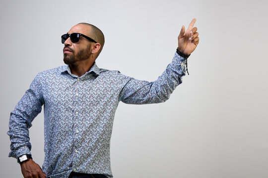 Cool, self-confident Latino man with a beard and a shirt, pointing his finger up, isolated on a white background