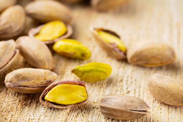 Roasted pistachios nuts. Fried and salty pistachios on wooden background. Close-up