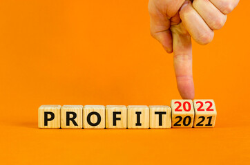 Planning 2022 profit new year symbol. Businessman turns wooden cubes and changes words 'profit 2021' to 'profit 2022'. Beautiful orange background, copy space. Business, 2022 profit new year concept.