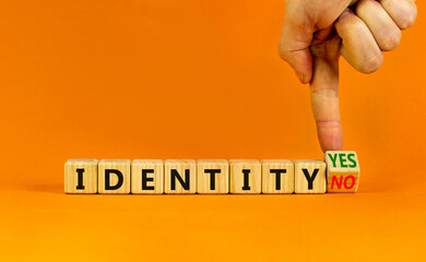 Identity symbol. Businessman turns a wooden cube and change words 'identity no' to 'identity yes'. Beautiful orange background. Business and identity concept, copy space.