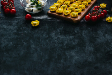 Italian pasta homemade ravioli with ricotta, tomatoes and spinach on a wooden plate