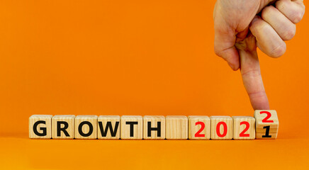 Planning 2022 growth new year symbol. Businessman turns wooden cubes and changes words 'Growth 2021' to 'Growth 2022'. Beautiful orange background, copy space. Business, 2022 growth new year concept.