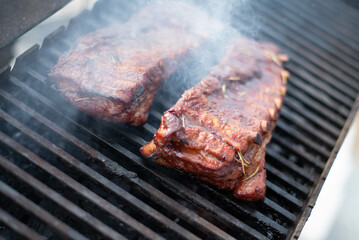 grilling baby back pork ribs over flaming grill.