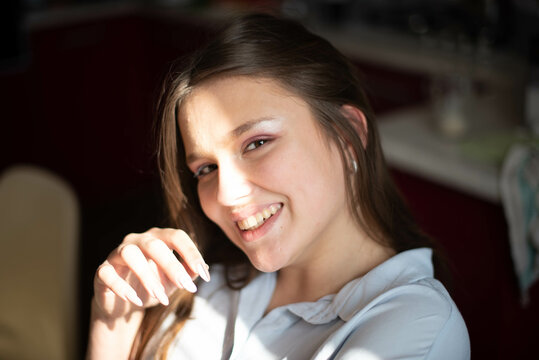 Fashion lifestyle image of pretty teenage young woman sitting in kitchen. Natural beauty.
