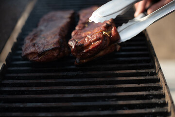 grilling baby back pork ribs over flaming grill.