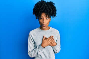 African american woman with afro hair wearing sportswear doing heart symbol with hands making fish face with mouth and squinting eyes, crazy and comical.