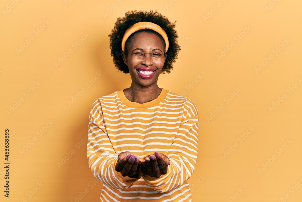 Canvas Prints Young african american woman holding hands together cupped, giving concept winking looking at the camera with sexy expression, cheerful and happy face.