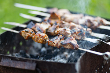 Barbecue meat on skewers. Cooking shashlik on the mangal in nature. Grilled kebab cooking on metal skewer. Home picnic