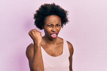 Fototapeta na wymiar Young african american woman wearing casual sleeveless t shirt angry and mad raising fist frustrated and furious while shouting with anger. rage and aggressive concept.
