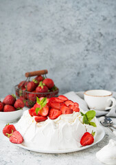 Pavlova cake with meringue and fresh strawberries on a light background, selective focus