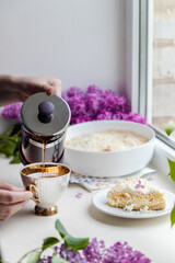 A female hand pours aromatic hot tea drink into a cup on the windowsill next to the window. Good morning wake up cheerful