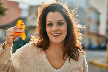 Young irish plus size girl smiling happy holding orange awareness ribbon at the city.