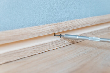 Setting a skirting board against the wall. Installation of plastic plinth