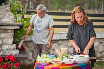 BBQ grilling party. Couple in garden making barbecue outdoors. Food, people and family time concept