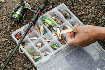 The fisherman prepares lures, wobblers and other fishing equipment. Preparation for fishing. A fishing tackle box 