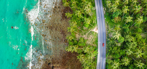 Aerial view of road between beautiful sea coastline green and summer coconut tree forest in Thailand. Travel destination concept