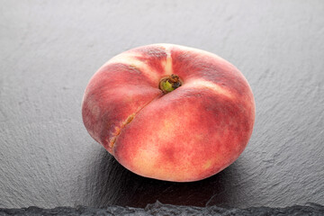 One organic ripe fig peach on a slate stone, close-up.