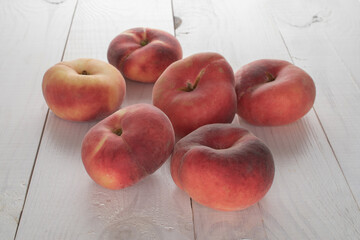 Several organic ripe fig peaches on a wooden table, close-up.