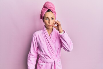 Young blonde woman wearing shower towel cap and bathrobe mouth and lips shut as zip with fingers....